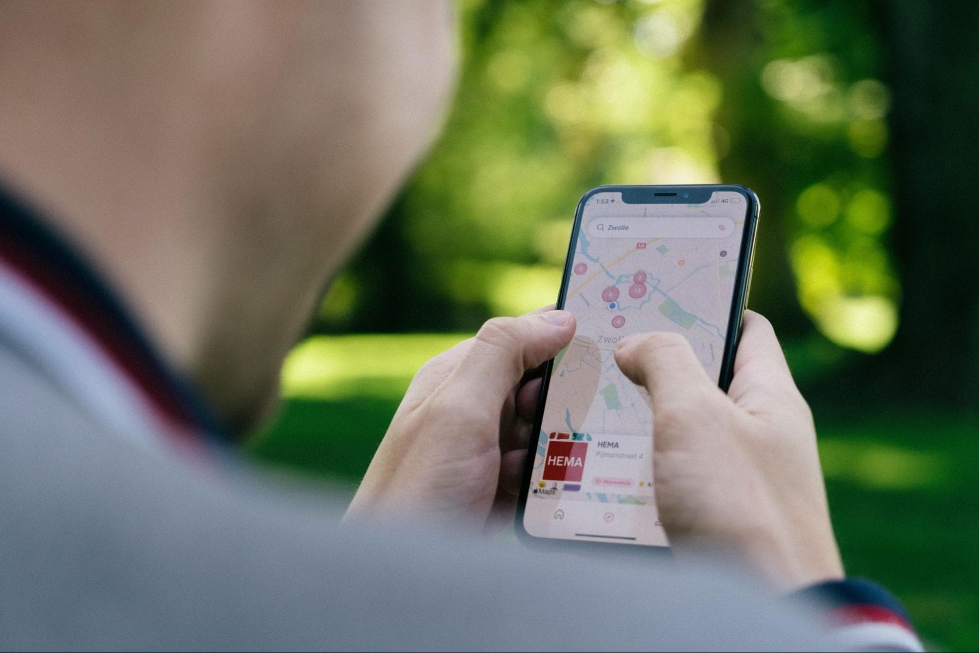 Person using smartphone with map app outdoors.