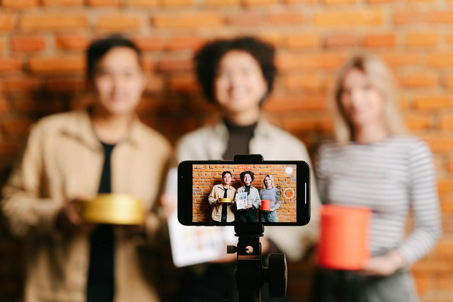 Smartphone capturing three people against brick wall